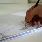A person's hand is crafting an art piece on a sheet of paper with a pencil. The pencil drawing features parts of a clock and some flowers, including leaves, in detailed strokes. Perfect for beginners, the sketchbook or papers are neatly stacked on a white surface.