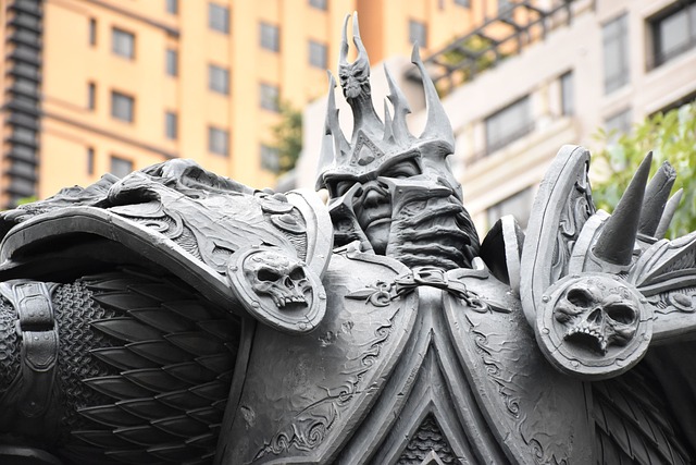 The statue of a medieval armored warrior with a horned helmet and elaborate shoulder armor featuring skulls stands fiercely against the backdrop of modern buildings. With intricate detailing, reminiscent of World of Warcraft characters, it highlights the warrior's fierce expression and battle-ready stance.